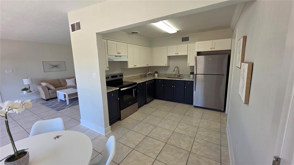 A kitchen with two-toned cabinets and stainless steel appliances opens into a living area — 3167 IRVING STREET, SARASOTA, FL