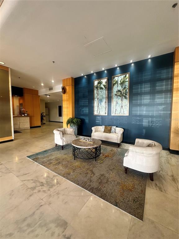 A lobby features a blue accent wall, two armchairs, a sofa, and a round coffee table — 880 MANDALAY AVENUE UNIT 309, CLEARWATER, FL