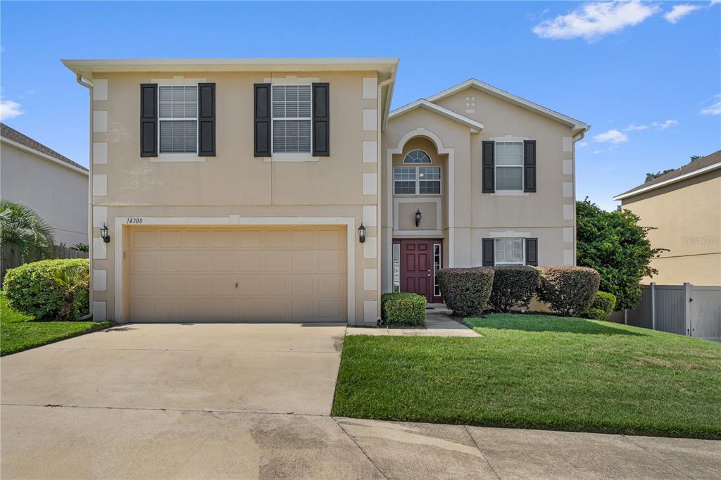 A two-story suburban house with a beige stucco exterior, a two-car garage, and shutters — 14308 NW 161ST AVENUE, ALACHUA, FL