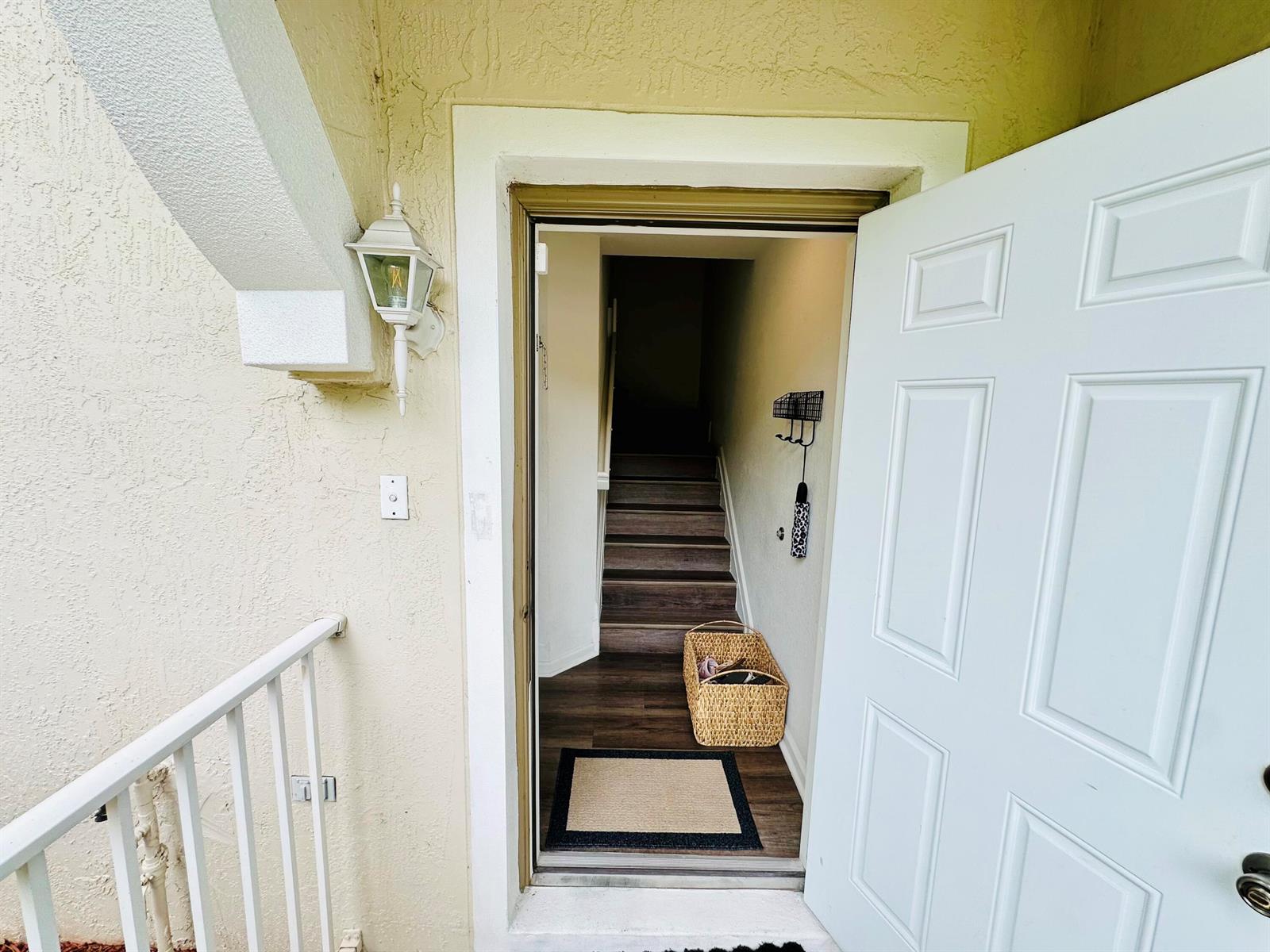 An open white door reveals an entryway with wood-look flooring and stairs leading upward — 4802 W Bexley Park Drive # A, Delray Beach FL 33445, DELRAY BEACH, FL