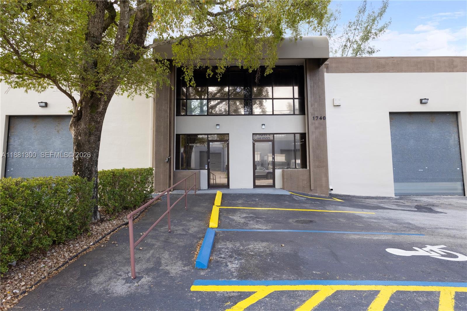 The exterior of a commercial building features two glass entry doors and two roll-up doors — 1740 NW 93 AV # 1740, Doral FL 33172, DORAL, FL