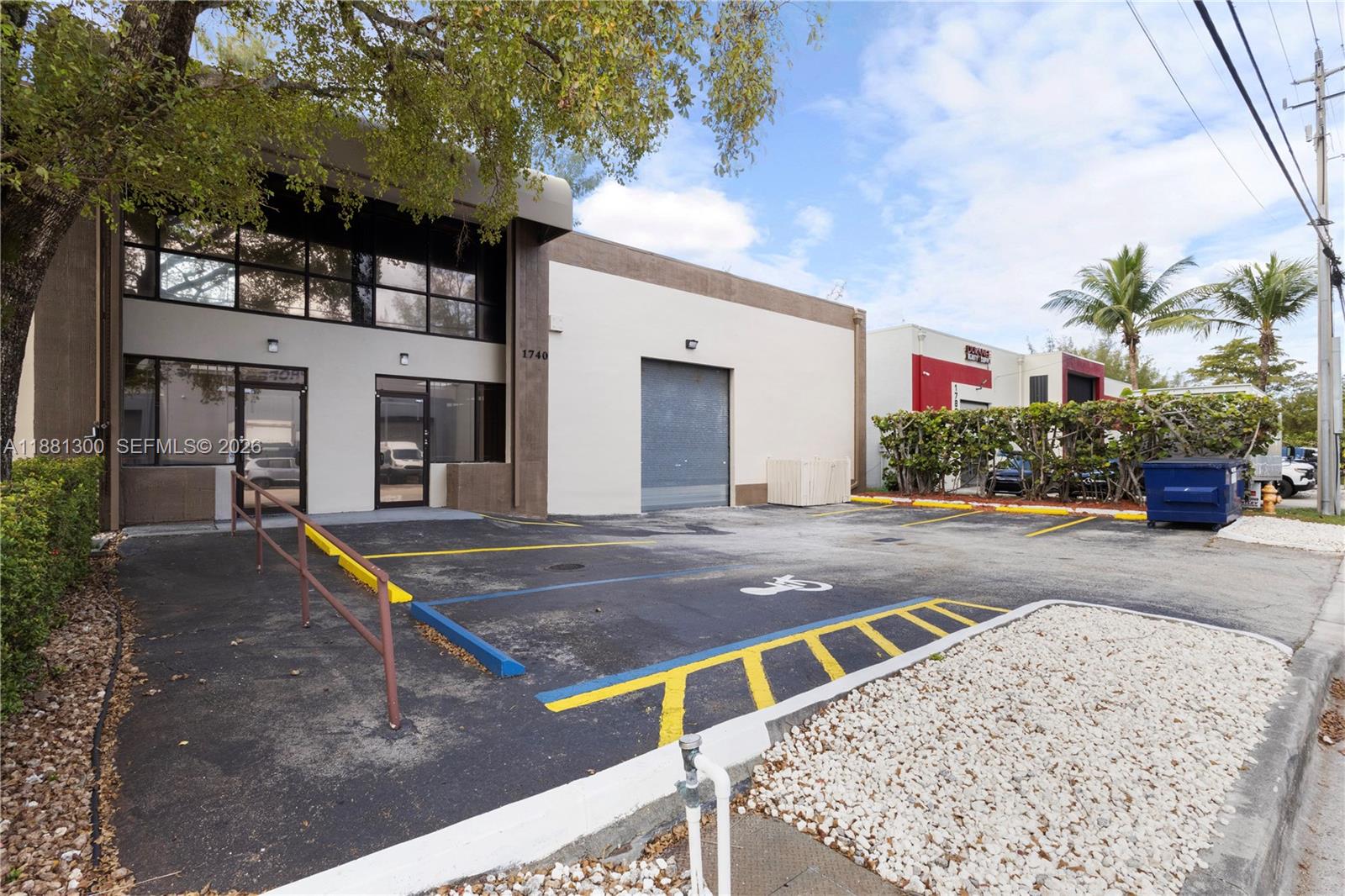 A commercial building exterior features a roll-up door, glass entrance, and a paved parking lot — 1740 NW 93 AV # 1740, Doral FL 33172, DORAL, FL
