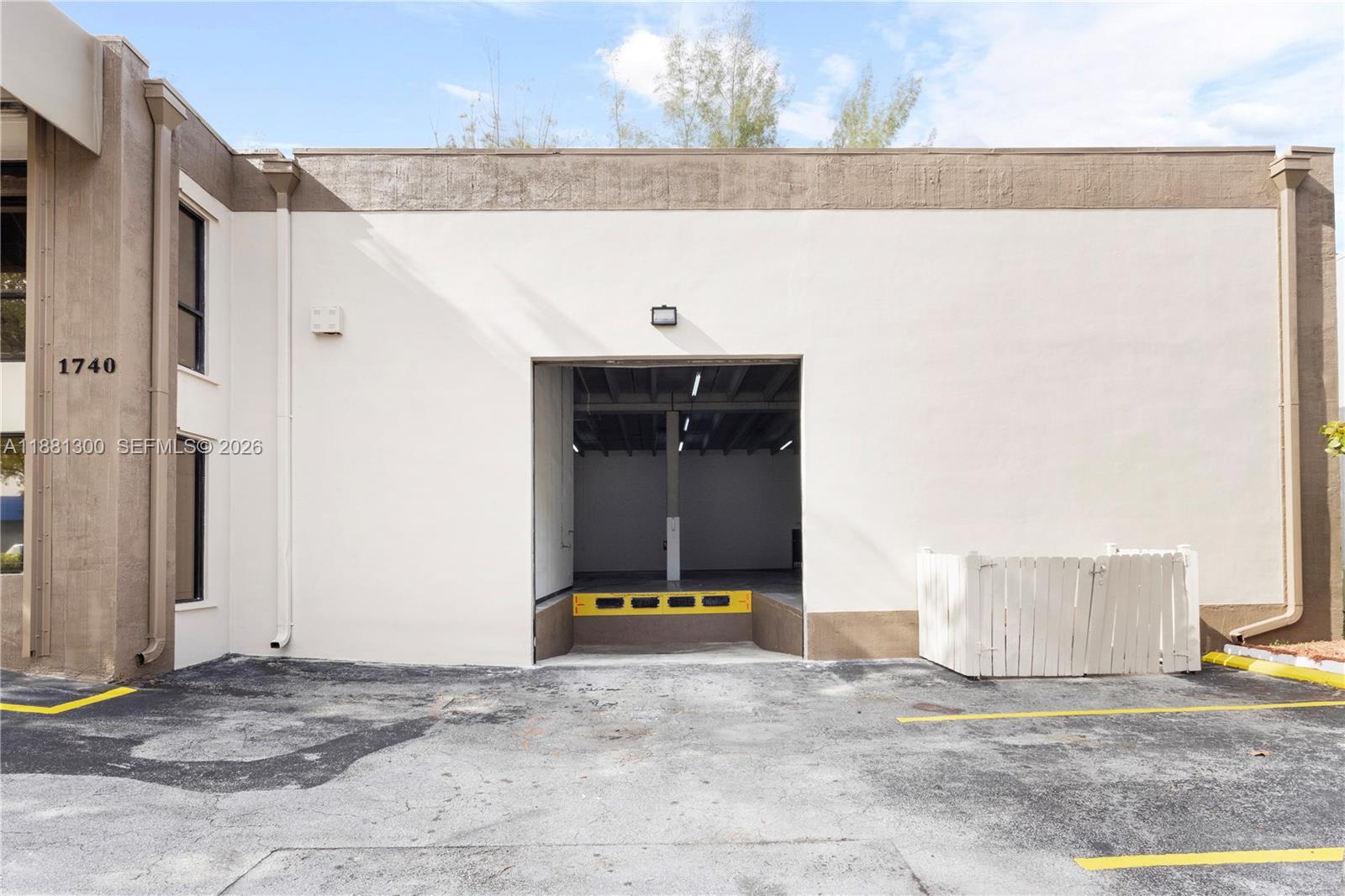 An exterior view of a commercial building featuring a loading dock and a large bay door — 1740 NW 93 AV # 1740, Doral FL 33172, DORAL, FL