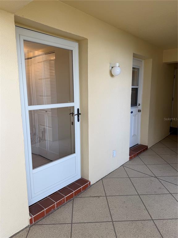 A covered outdoor walkway features two white doors with glass panels and tiled flooring — 3808 GULF OF MEXICO DRIVE UNIT E105, LONGBOAT KEY, FL