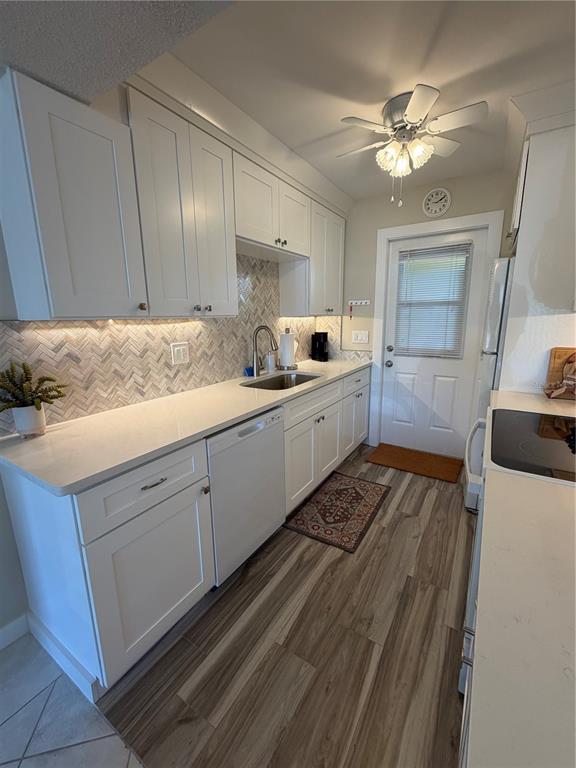 A kitchen features white cabinets, quartz countertops, a herringbone backsplash, and wood-look flooring — 3808 GULF OF MEXICO DRIVE UNIT E105, LONGBOAT KEY, FL