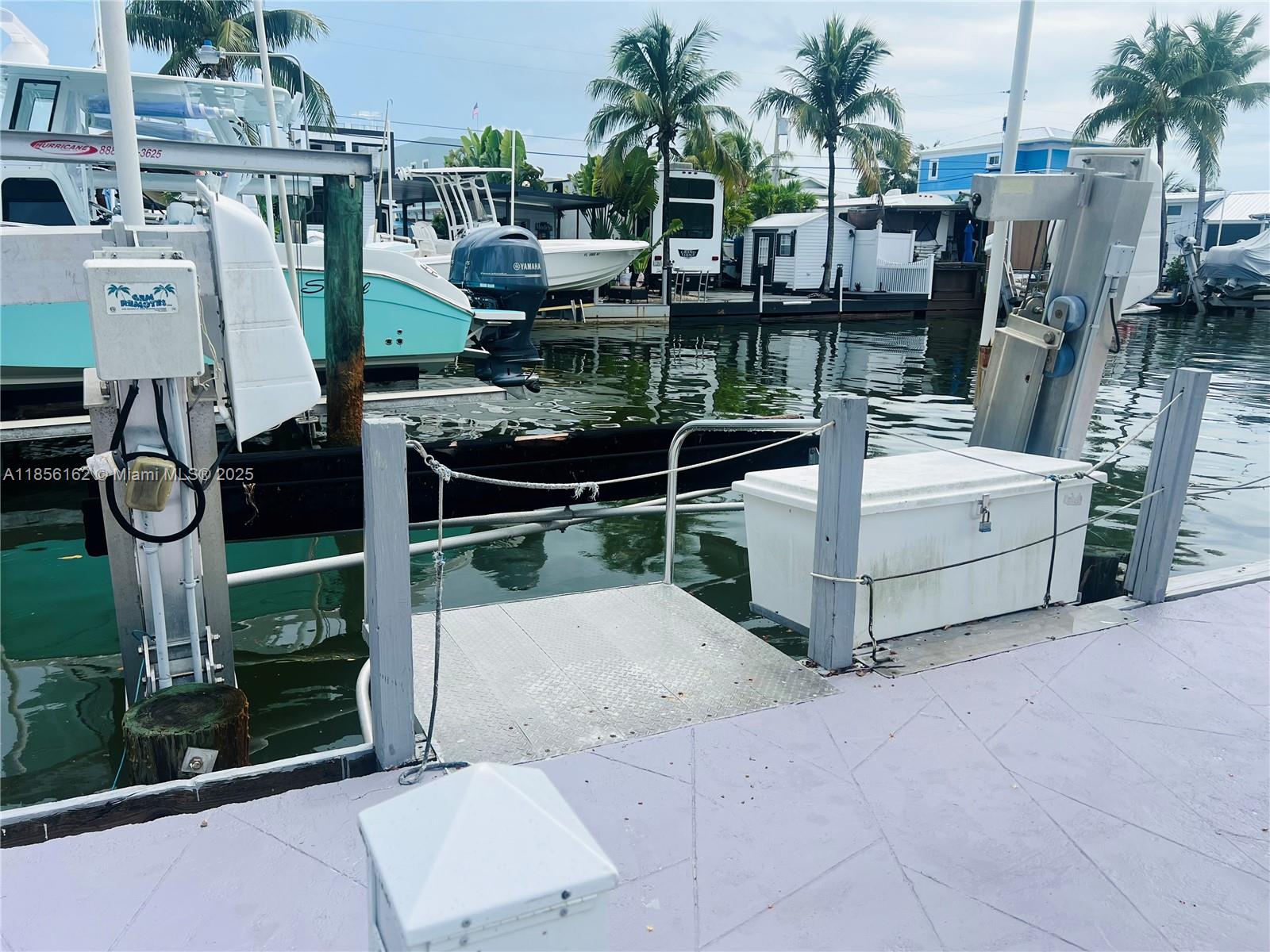 A boat lift and a metal boarding platform are situated on a dock by the water — 325 Calusa St Lot 301, Key Largo FL 33037, KEY LARGO, FL