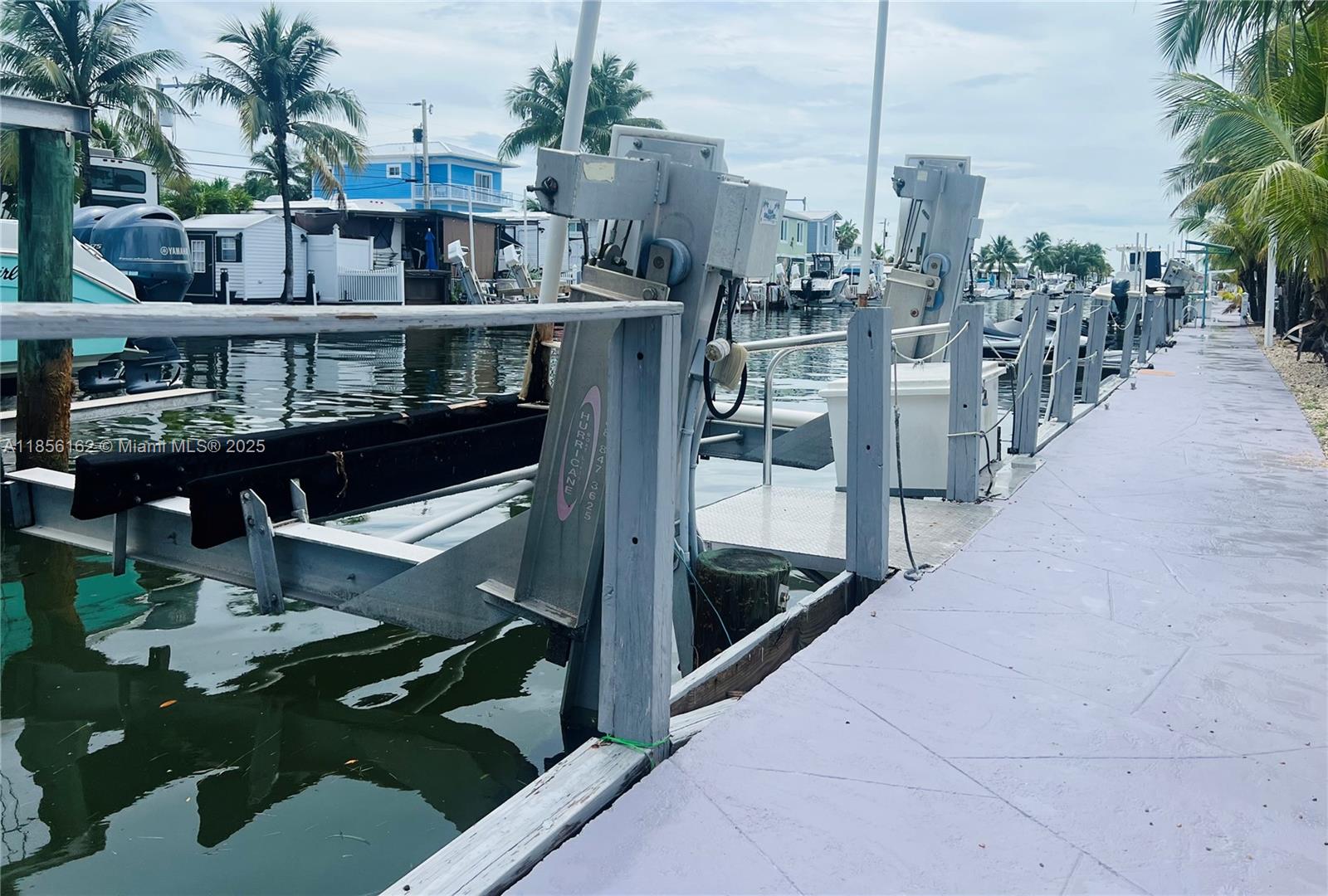 A boat lift mechanism is installed on a wooden dock along a canal — 325 Calusa St Lot 301, Key Largo FL 33037, KEY LARGO, FL