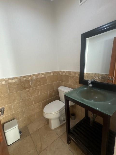 A bathroom features a glass vessel sink, dark wood vanity, toilet, and tan tiled walls — 1124 MANSIONES DE VISTAMAR MARINA III, CAROLINA, PR