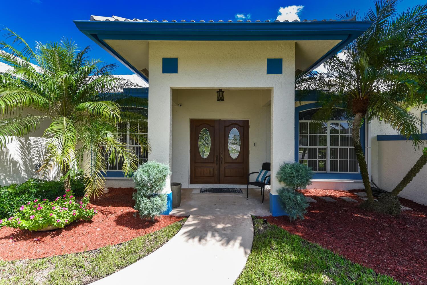 A tiled entryway features double wooden front doors, a console table, and a bedroom view — 1935 Primrose Lane, Wellington FL 33414, WELLINGTON, FL