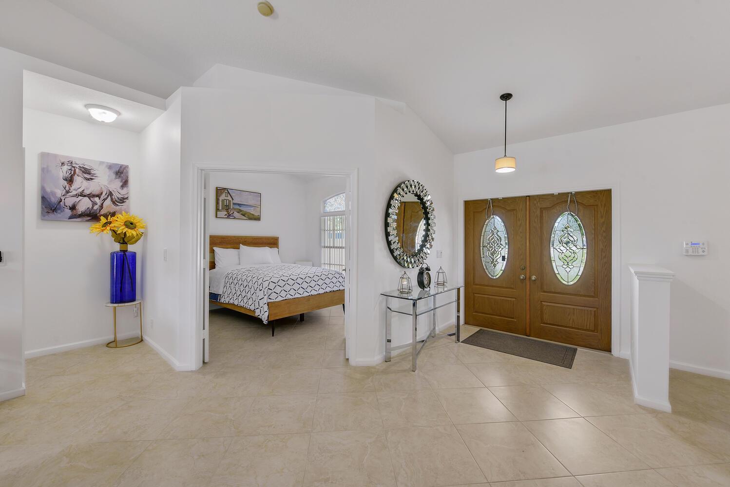 A dining room features a wooden table with six chairs, a chandelier, and floral wall art — 1935 Primrose Lane, Wellington FL 33414, WELLINGTON, FL