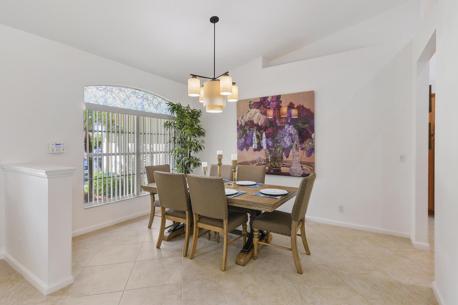 A bedroom features a wooden bed frame, tile flooring, and a large window with stained glass — 1935 Primrose Lane, Wellington FL 33414, WELLINGTON, FL