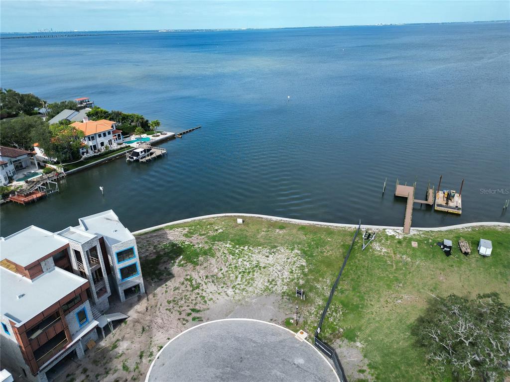 An aerial view shows a waterfront lot with a modern house under construction and docks — 5028 W LEONA STREET, TAMPA, FL
