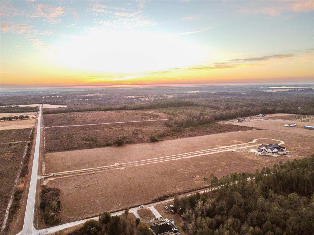 An aerial view shows a large, cleared plot of land with a house under construction — 4299 ROYAL SKY (LOT 3) COURT, BROOKSVILLE, FL