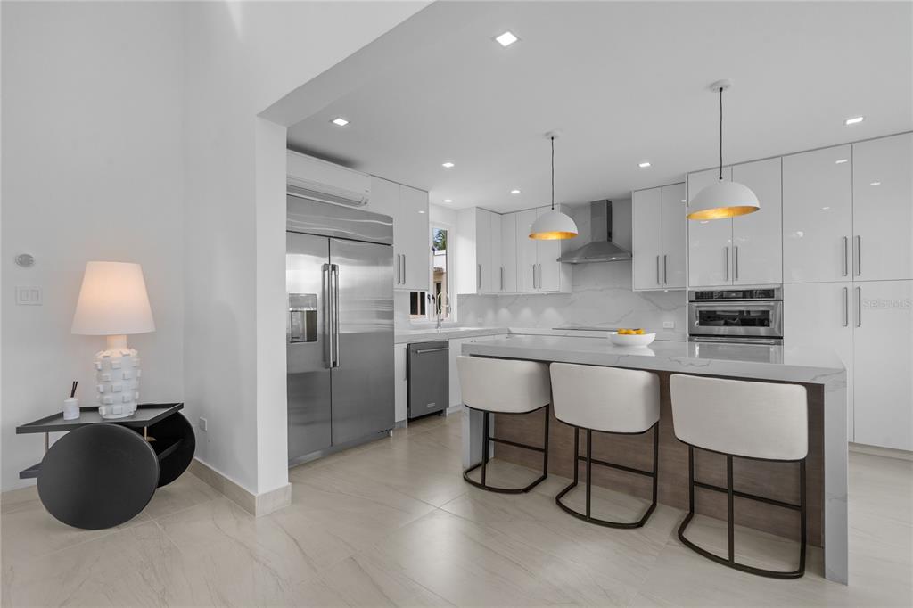 A modern kitchen features white cabinetry, a marble-topped island with three stools, and stainless appliances — 86 LAKESIDE VILLAS UNIT Y4, DORADO, PR