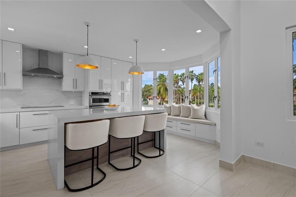 A modern white kitchen features a waterfall island, bar stools, and a window seat — 86 LAKESIDE VILLAS UNIT Y4, DORADO, PR