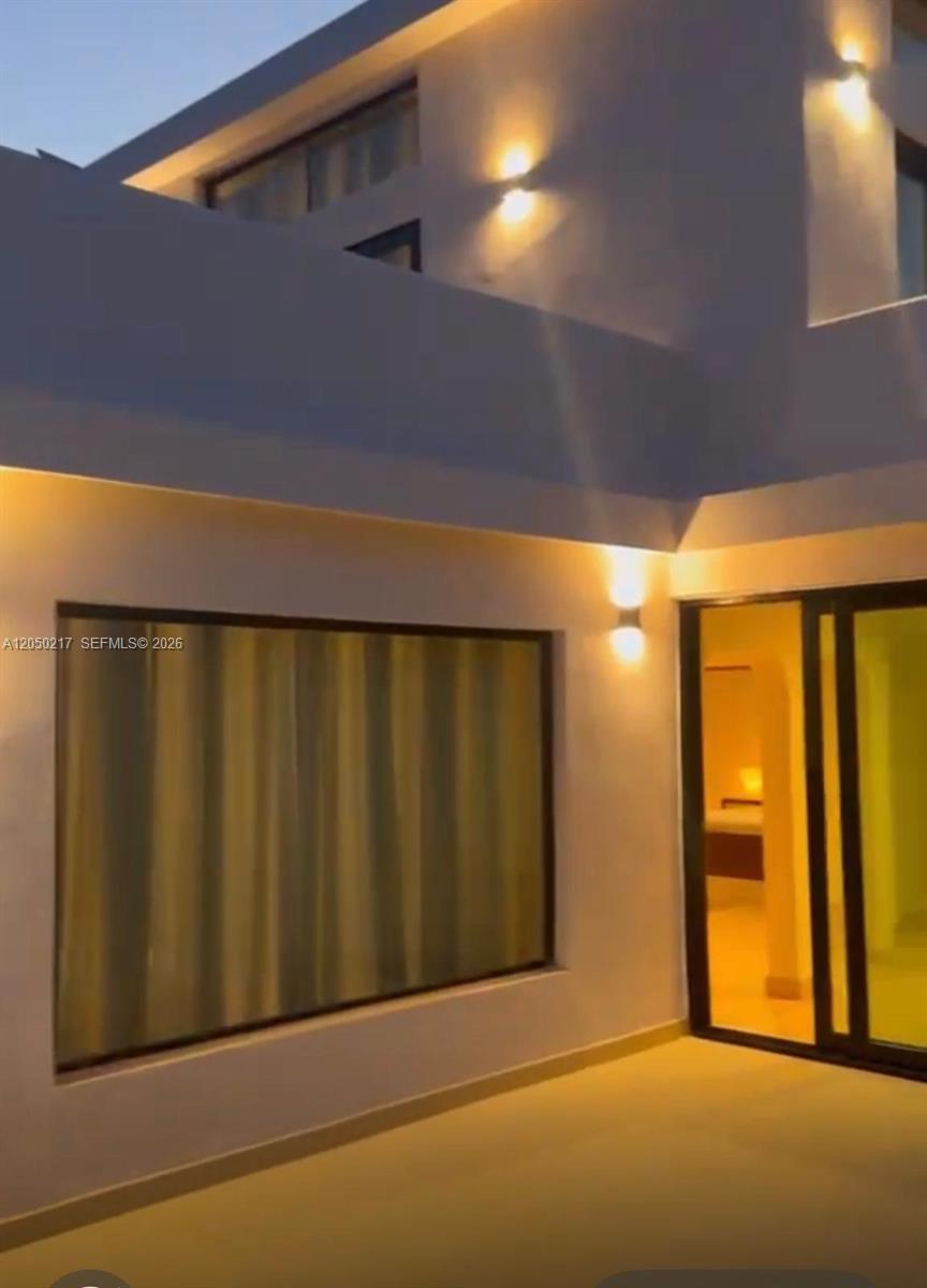 A modern exterior patio features a large window, sliding glass doors, and wall-mounted lighting — 0 LA NOVILLA, AK 99999, AK