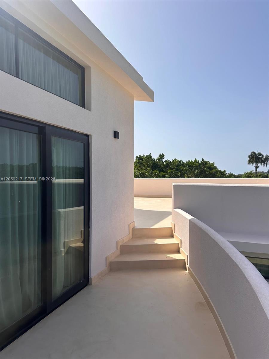 A modern balcony features white walls, a sliding glass door, and steps leading to a terrace — 0 LA NOVILLA, AK 99999, AK