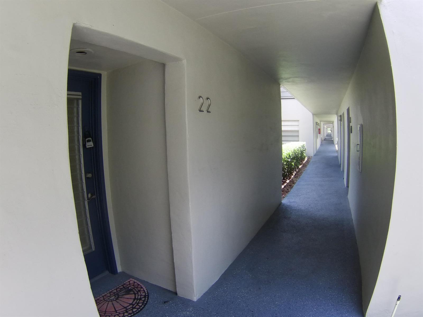 An outdoor apartment hallway with a blue door labeled 22 and a concrete walkway — 22 CAPRI A, Delray Beach FL 33484, DELRAY BEACH, FL