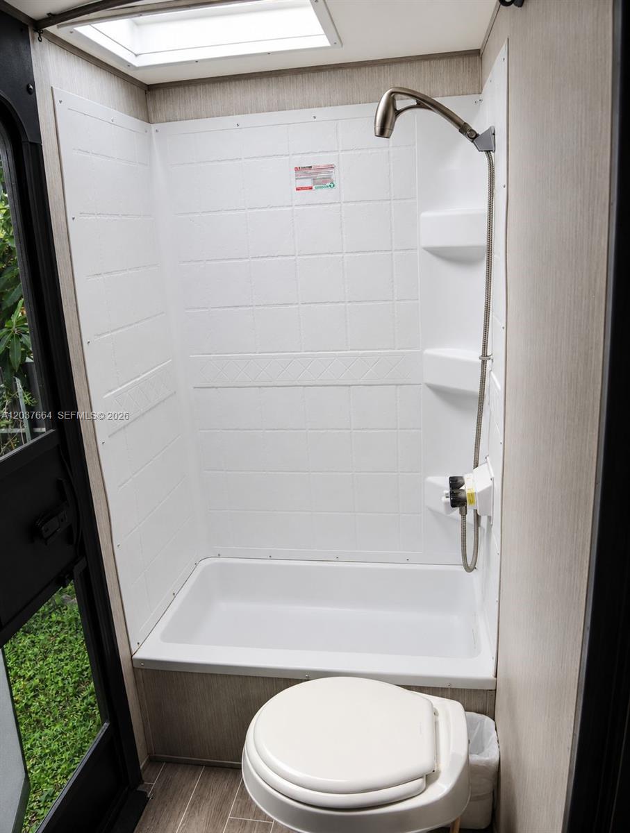 A small RV bathroom features a white shower stall, a toilet, and a skylight — 735 NE 162nd St # B, Miami FL 33162, MIAMI, FL