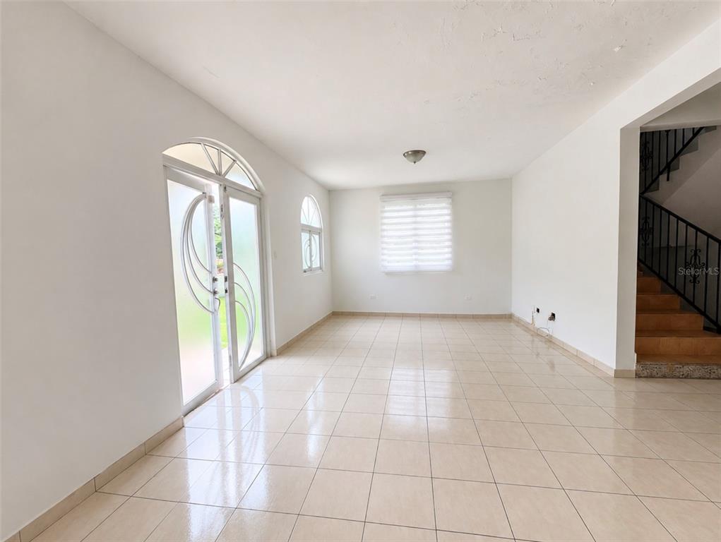 An empty room with beige tile flooring, white walls, and two ceiling light fixtures — Urb. Morovis del Norte #614 CALLE URUGUAY, MOROVIS, PR