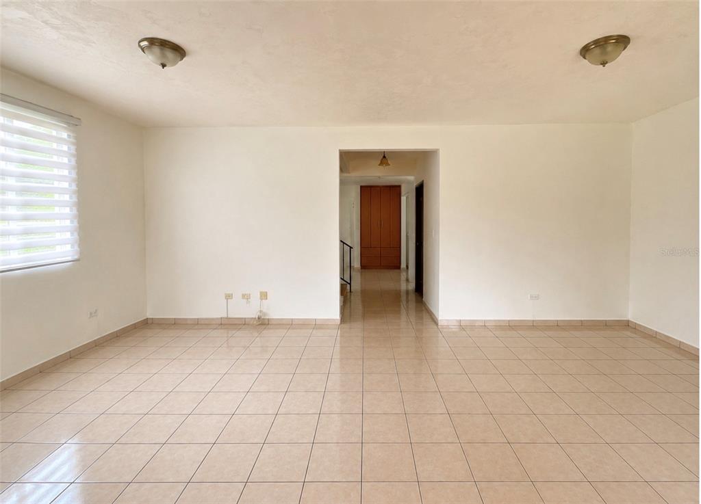 A dining room features a light-colored table, six chairs, and a window with blinds — Urb. Morovis del Norte #614 CALLE URUGUAY, MOROVIS, PR