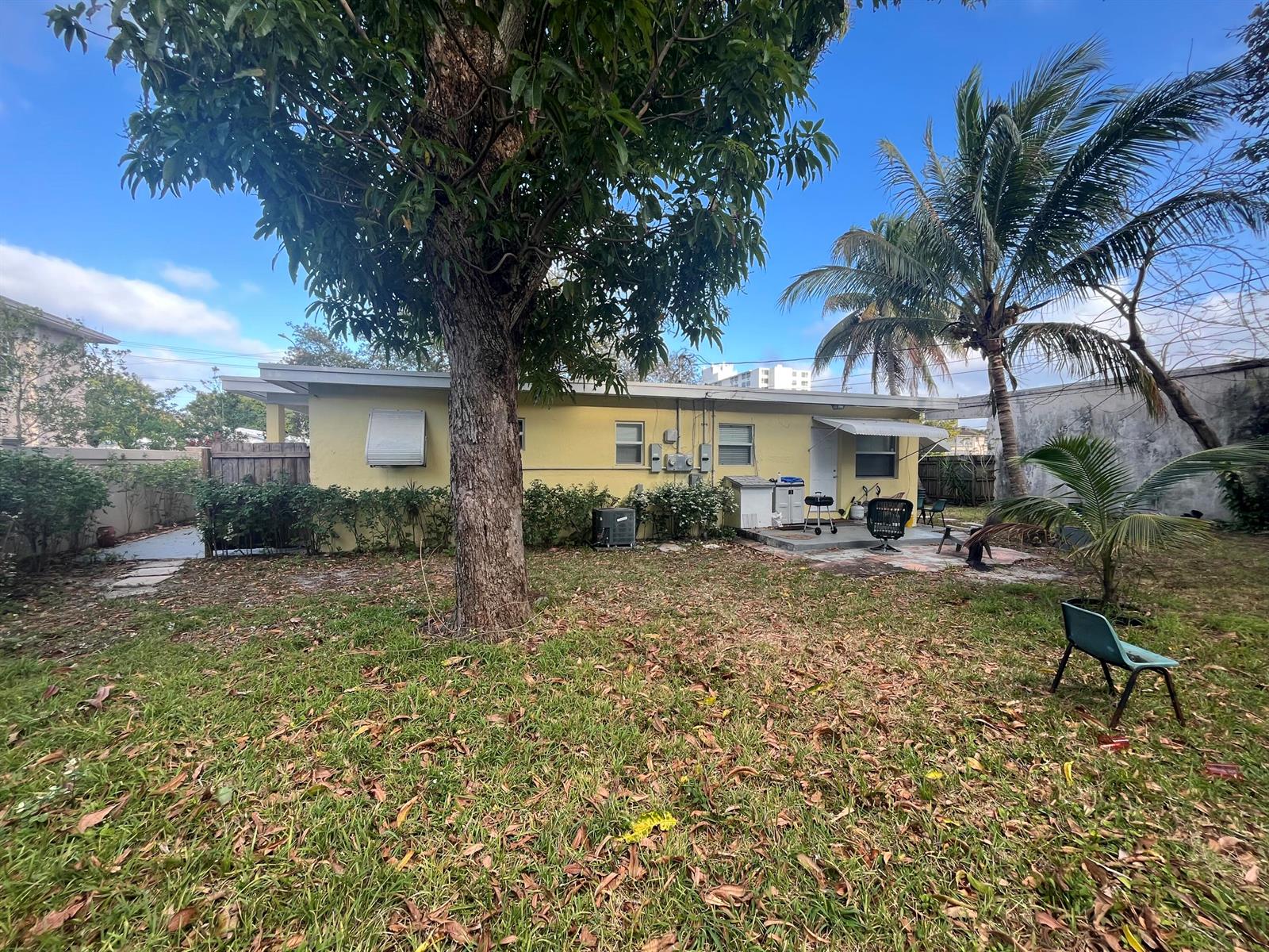 A yellow one-story house with a large tree in the backyard and a patio area — 211 N A Street, FL 33460, FL