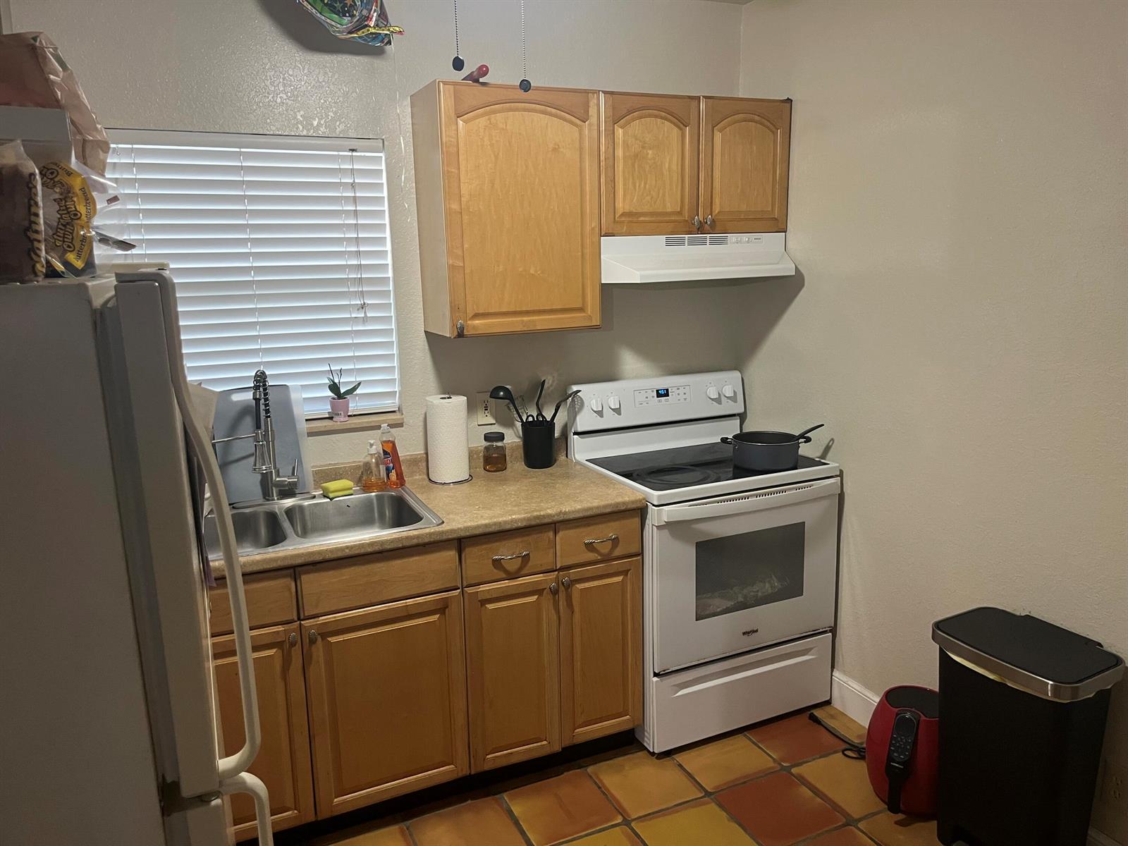 A kitchen features wood cabinets, white appliances, a double sink, and terracotta floor tiles — 211 N A Street, FL 33460, FL