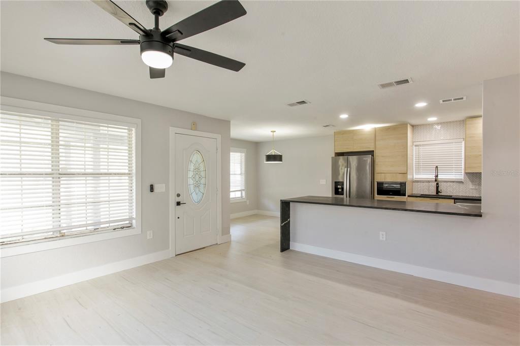 A bright, open-concept living area features light wood flooring, a kitchen island, and a ceiling fan — 822 POLK STREET, ORLANDO, FL