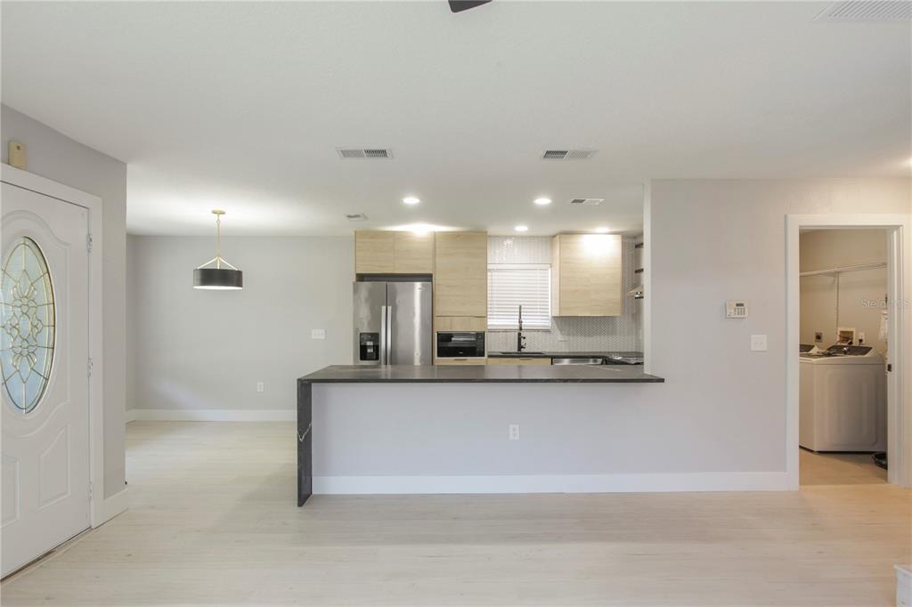 A kitchen with light wood cabinets and a dark countertop overlooks an open living area — 822 POLK STREET, ORLANDO, FL