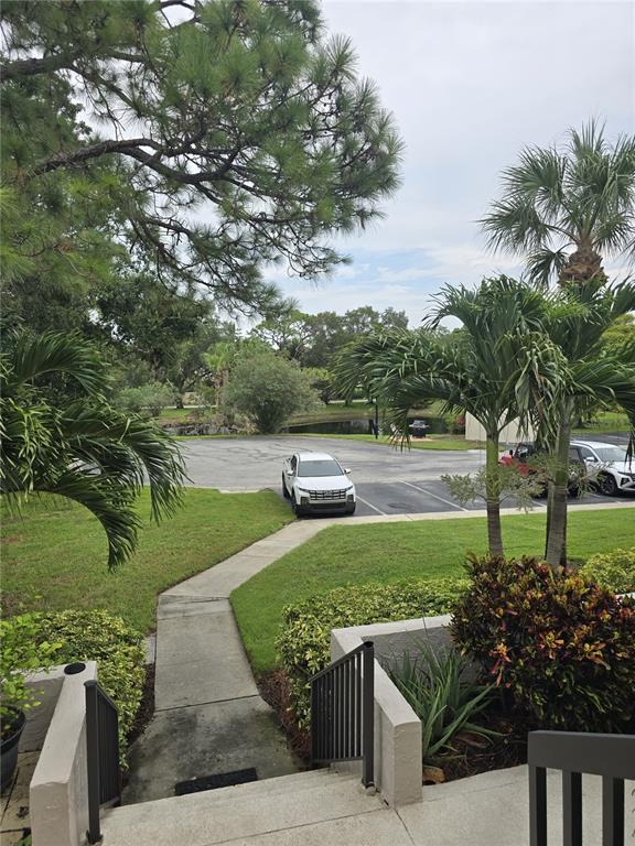 A concrete walkway leads from a set of stairs toward a parking lot with cars — 1802 MARINER DR UNIT 32, TARPON SPRINGS, FL