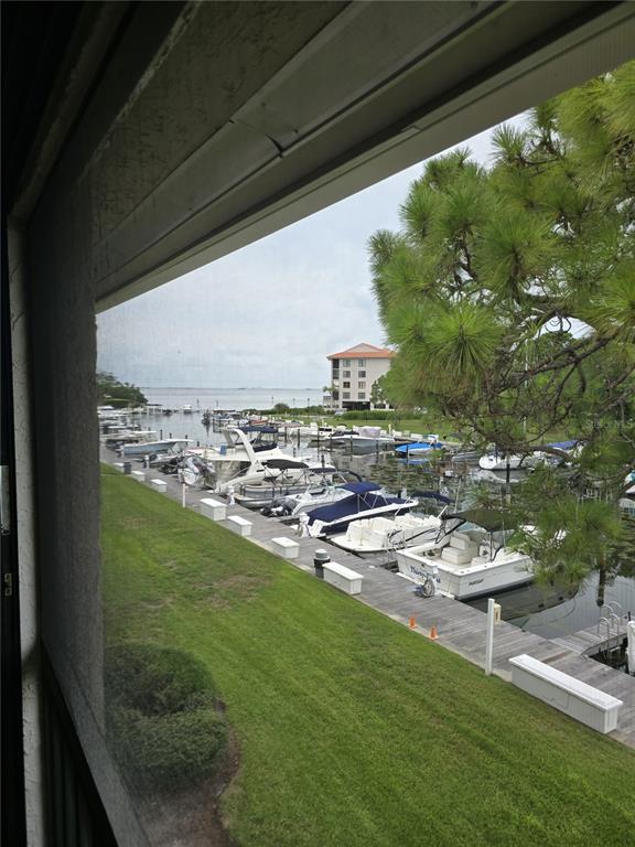 A view from a screened balcony overlooking a marina with docked boats and a building — 1802 MARINER DR UNIT 32, TARPON SPRINGS, FL