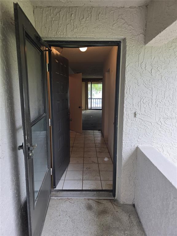 An open front door reveals a tiled entryway leading to a living area with balcony access — 1802 MARINER DR UNIT 32, TARPON SPRINGS, FL