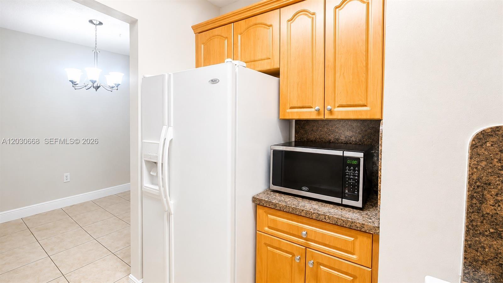 A white refrigerator stands next to a microwave on a counter with wooden cabinets — 9100 SW 137th Ter # 3, Miami FL 33176, MIAMI, FL