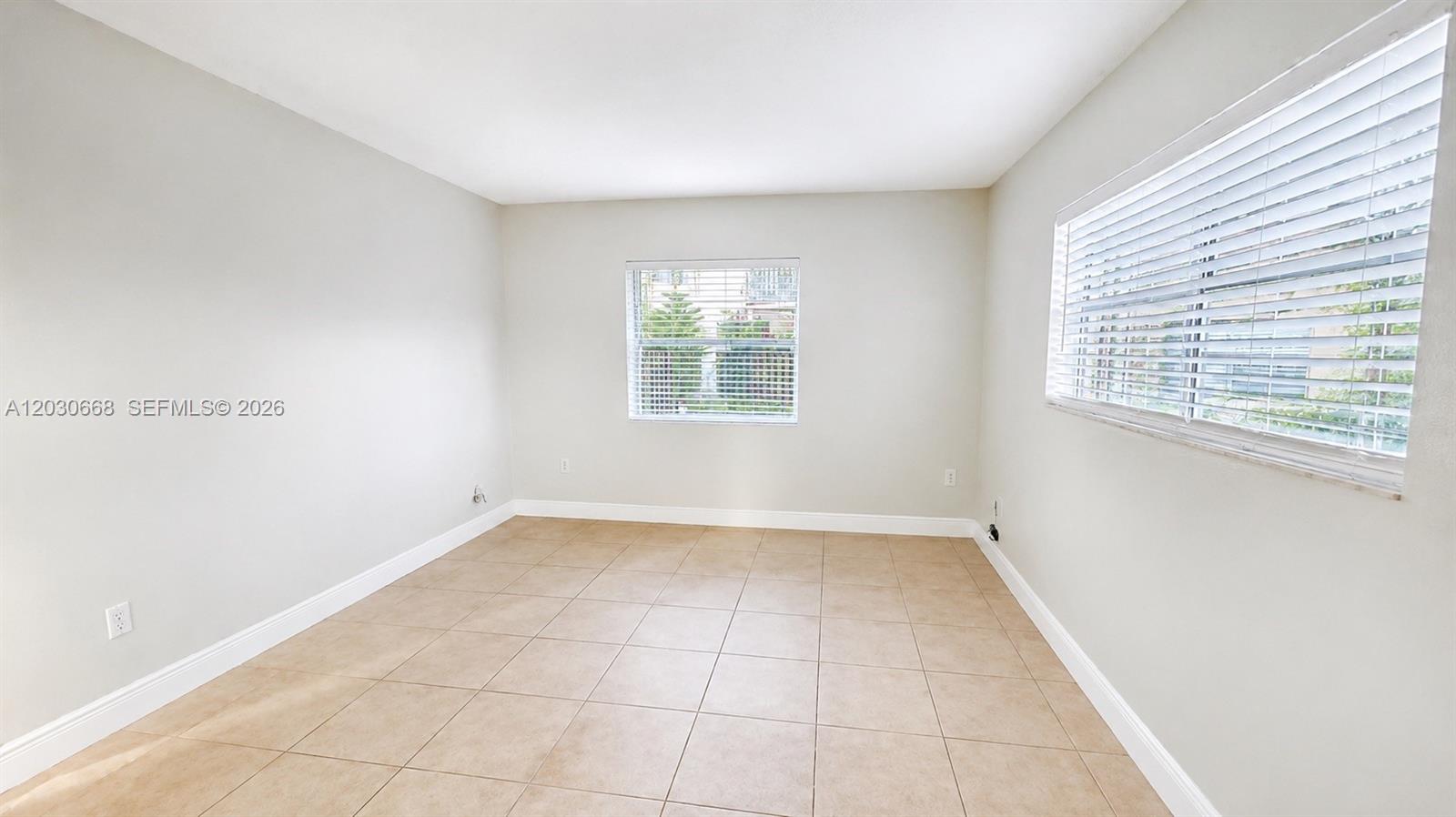 An empty room features light-colored walls, beige tile flooring, and two windows with blinds — 9100 SW 137th Ter # 3, Miami FL 33176, MIAMI, FL