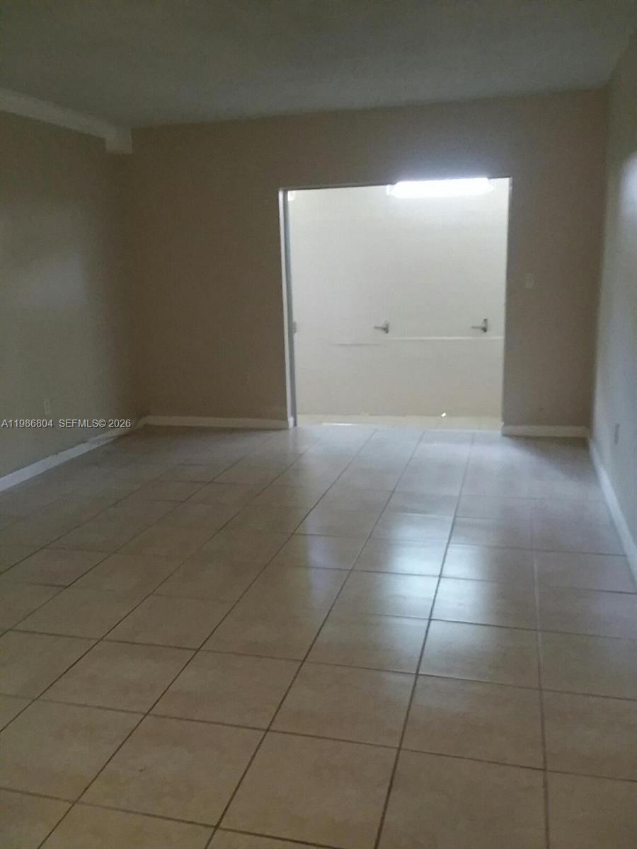 An empty room with light-colored tile flooring leads into a smaller, adjacent space — 140 Royal Palm Rd # 107, Hialeah Gardens FL 33016, HIALEAH GARDENS, FL