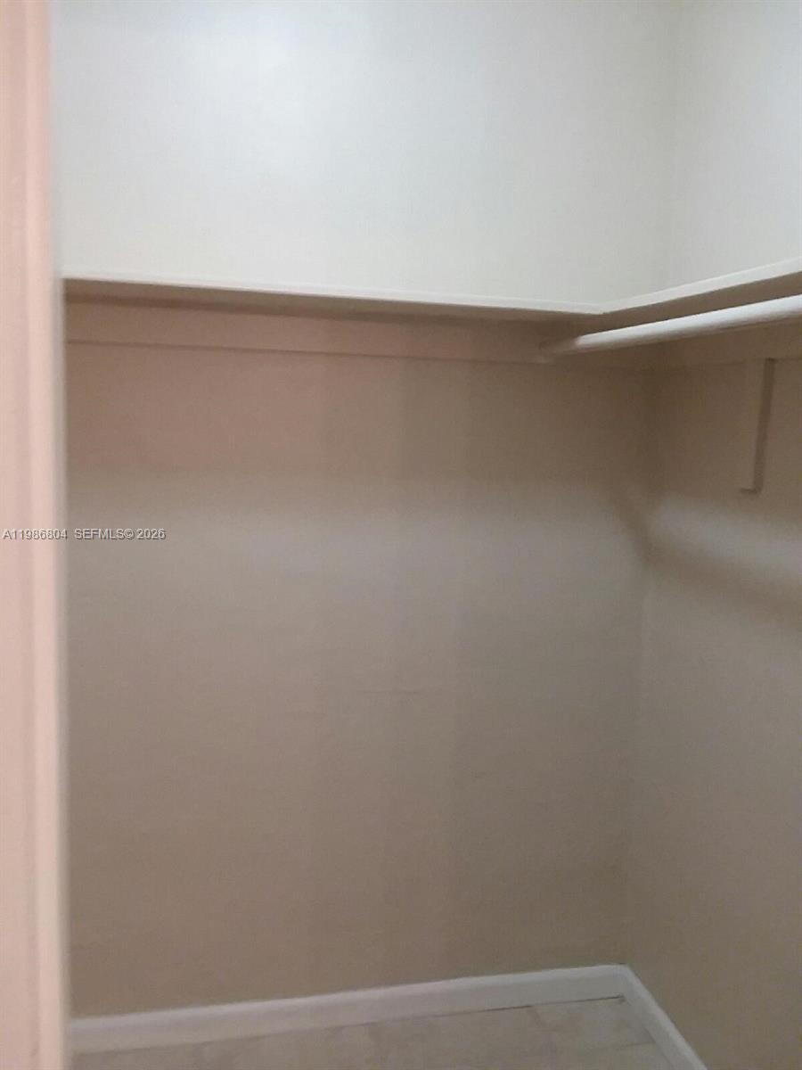 A walk-in closet features a white shelf and a hanging rod against plain walls — 140 Royal Palm Rd # 107, Hialeah Gardens FL 33016, HIALEAH GARDENS, FL