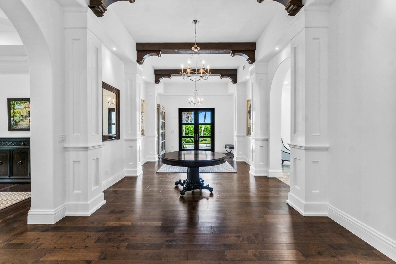 A grand foyer features dark hardwood floors, white paneled columns, and a central round table — 1904 SE Sailfish Point Boulevard, Stuart FL 34996, STUART, FL