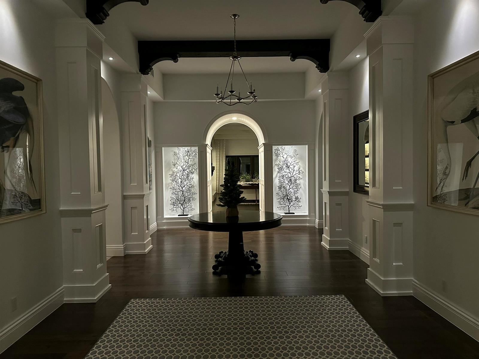 A grand foyer features dark wood floors, white columns, a round table, and decorative wall art — 1904 SE Sailfish Point Boulevard, Stuart FL 34996, STUART, FL