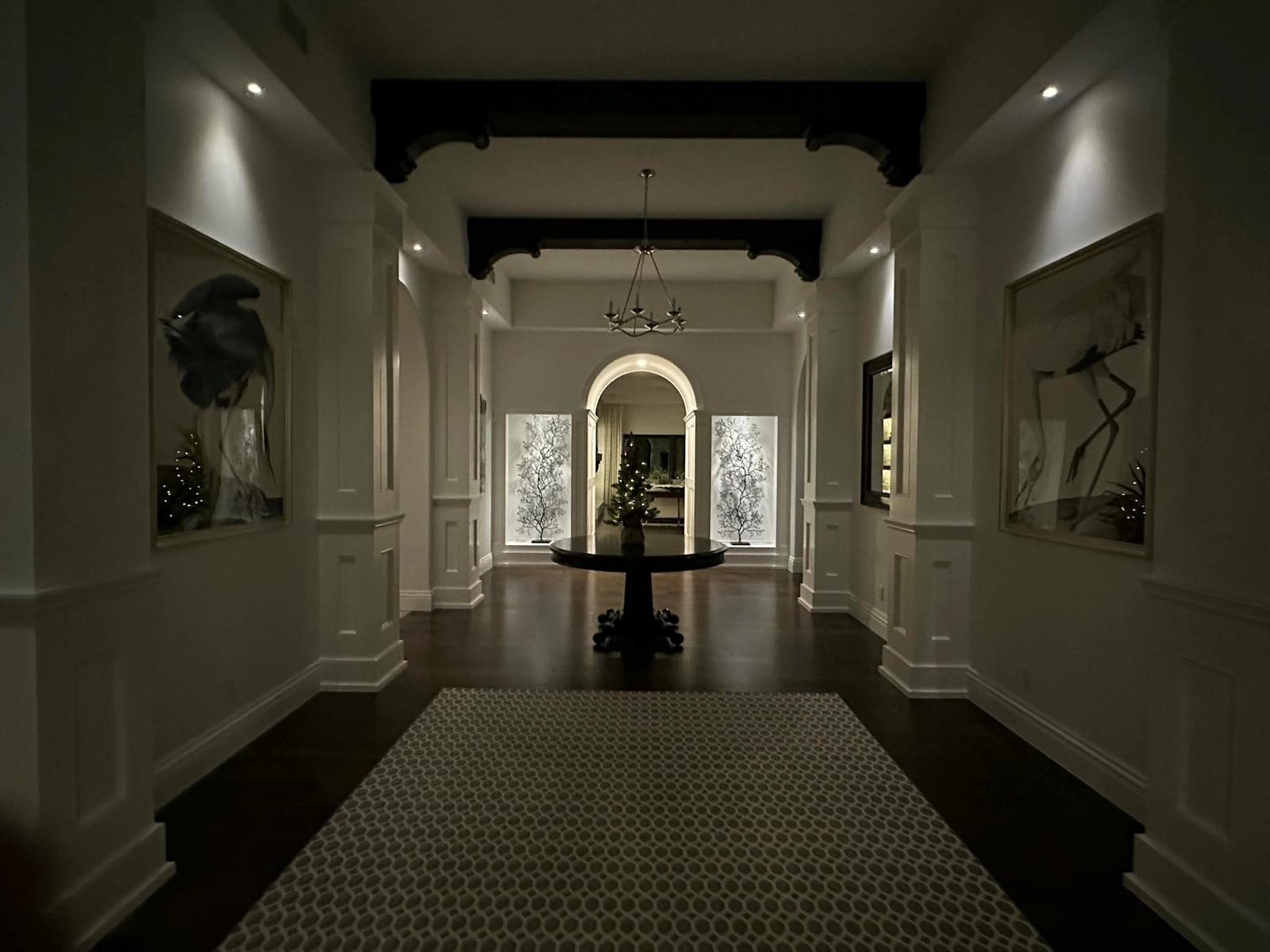 A dimly lit foyer features a round table, dark wood flooring, and arched architectural details — 1904 SE Sailfish Point Boulevard, Stuart FL 34996, STUART, FL