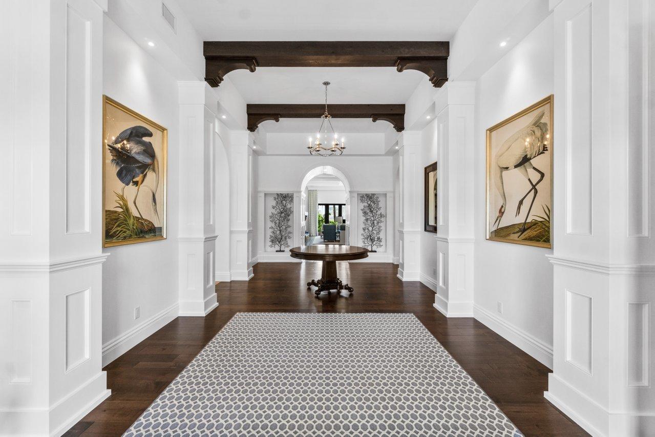 A bright foyer features dark wood floors, white wainscoting, ceiling beams, and a round table — 1904 SE Sailfish Point Boulevard, Stuart FL 34996, STUART, FL