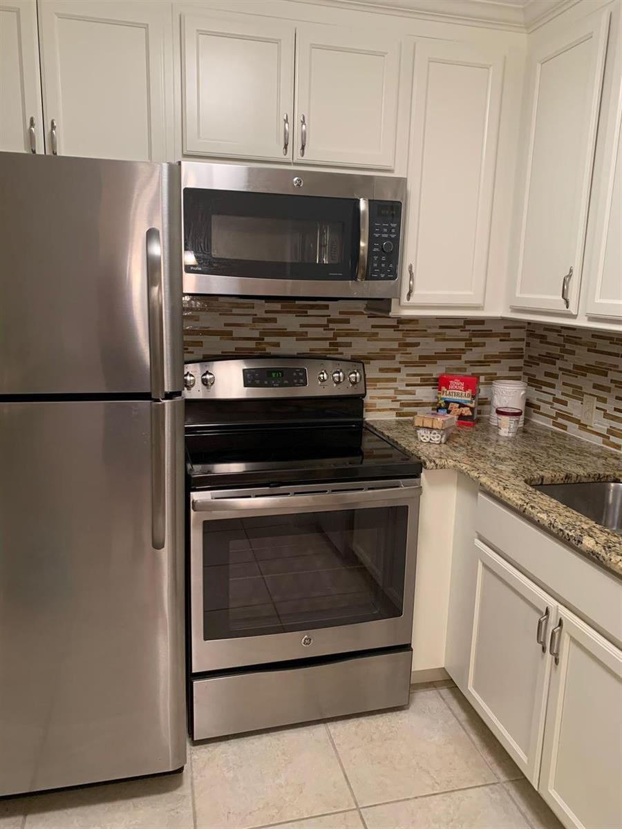 A kitchen features white cabinets, stainless steel appliances, granite countertops, and a tiled backsplash — 87 FANSHAW C # 87, Boca Raton FL 33434, BOCA RATON, FL