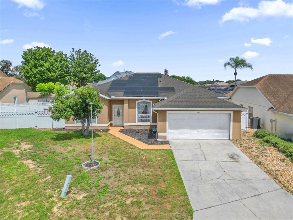 A single-story house with a tan stucco exterior, a two-car garage, and rooftop solar panels — 5403 LOMA VISTA LOOP, DAVENPORT, FL