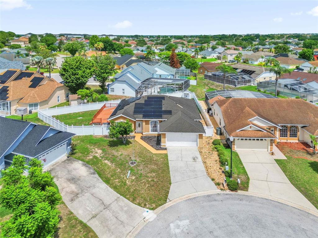 An aerial view shows a suburban house with solar panels and a backyard pool enclosure — 5403 LOMA VISTA LOOP, DAVENPORT, FL