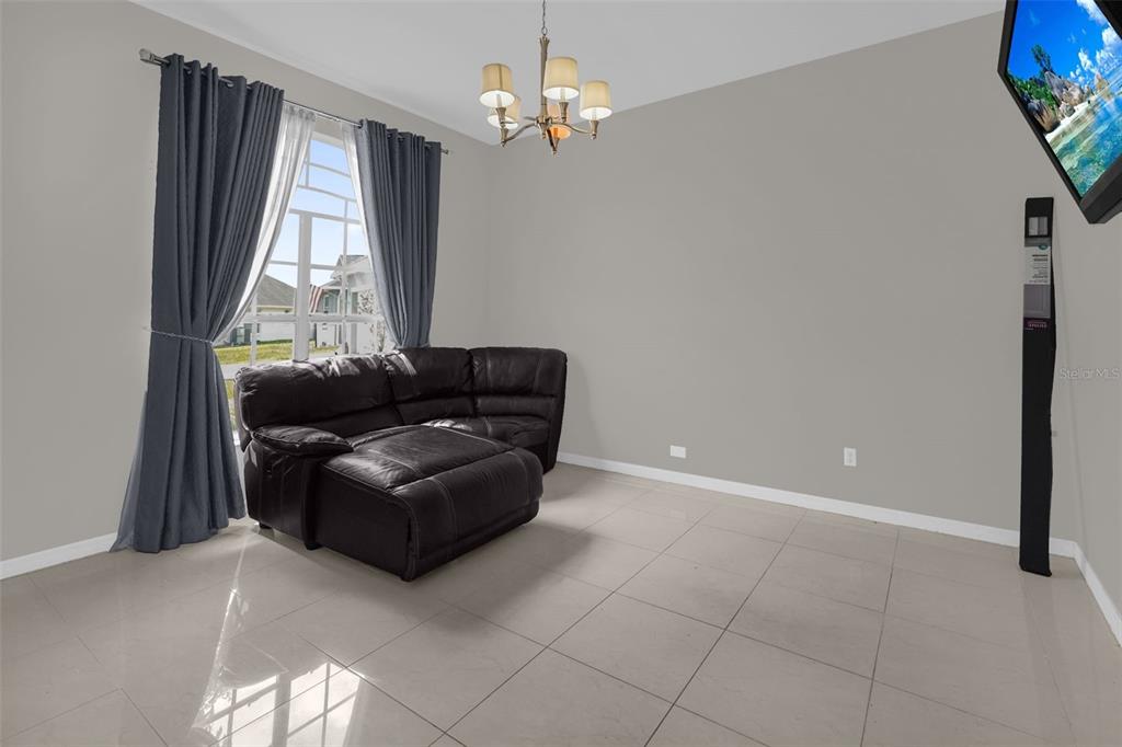 A living room features a dark leather sectional, tile flooring, and a chandelier — 5403 LOMA VISTA LOOP, DAVENPORT, FL