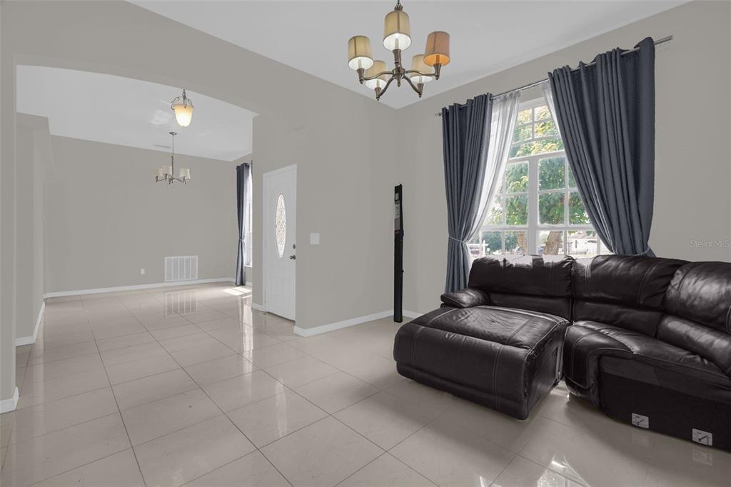 A living room features light tile flooring, a black leather sectional, and a chandelier — 5403 LOMA VISTA LOOP, DAVENPORT, FL
