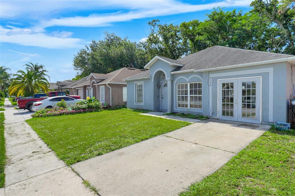 A light blue single-story house with a concrete driveway and a front lawn — 7544 PINE FORK DRIVE, ORLANDO, FL