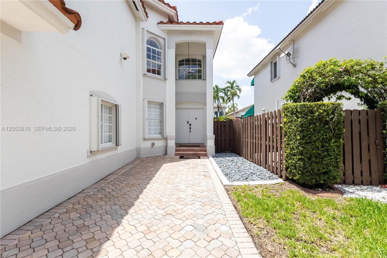 A paved driveway leads to the white exterior and front entrance of a two-story house — 10873 NW 71st St, Doral FL 33178, DORAL, FL