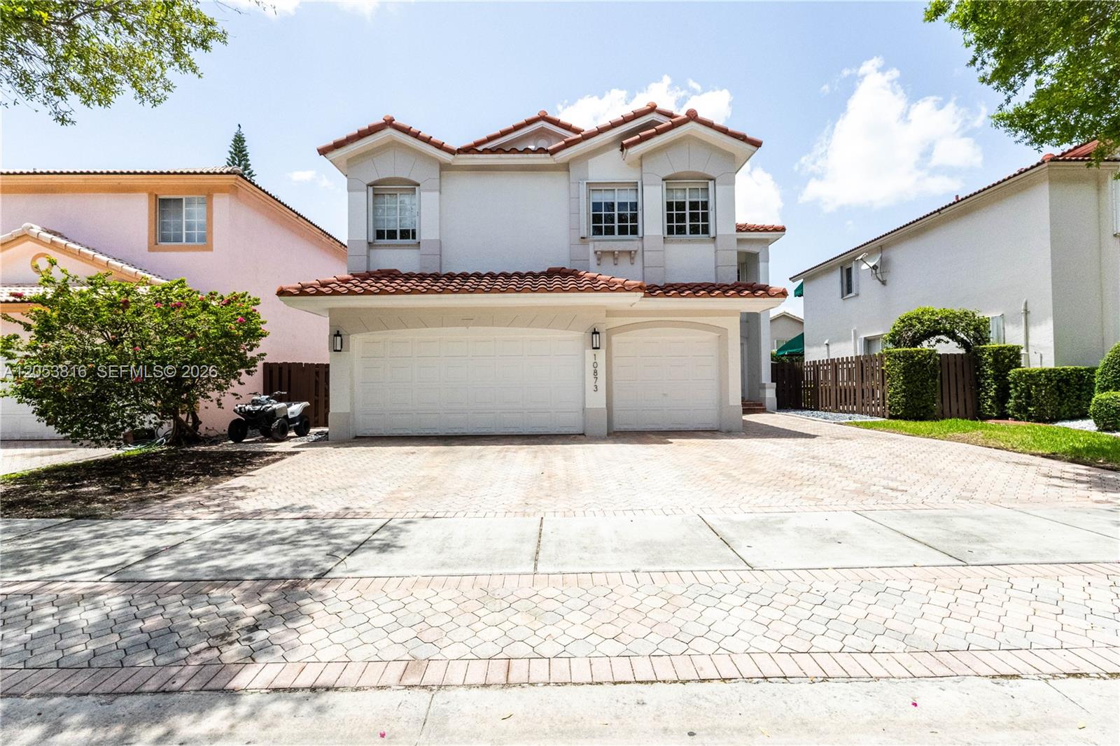 A two-story house with a tiled roof and a three-car garage sits on a paved driveway — 10873 NW 71st St, Doral FL 33178, DORAL, FL