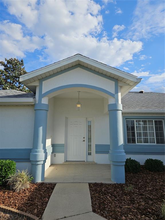 The exterior of a house features a covered entryway with two blue columns and a door — 5954 SW 98TH STREET ROAD, OCALA, FL