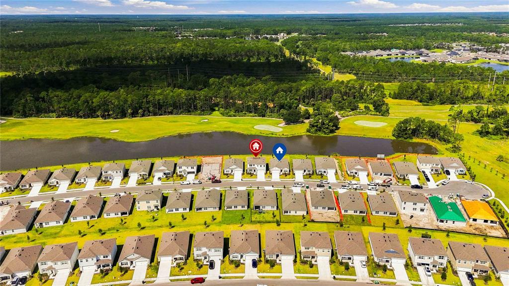 An aerial view shows a suburban neighborhood with houses bordering a golf course and lake — 1037 CHAMPION RDG DRIVE, DAYTONA BEACH, FL